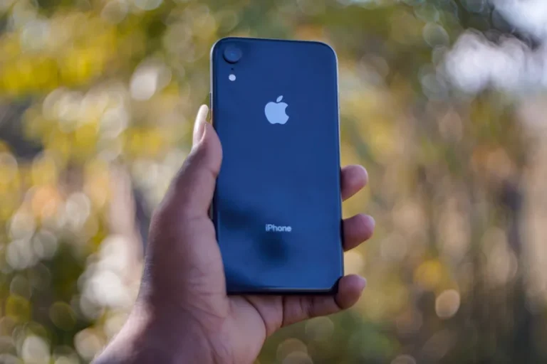 Apple Store passe à Liquid Glass en version 6.6, le panier reste sage A close-up shot of a person holding a smartphone with a blurred natural background.