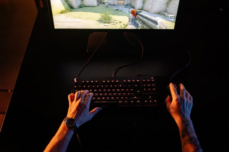 App Store Awards 2025 : 45 finalistes, Apple mise sur le quotidien A gamer intensely playing a first-person shooter game on a computer setup indoors at night.