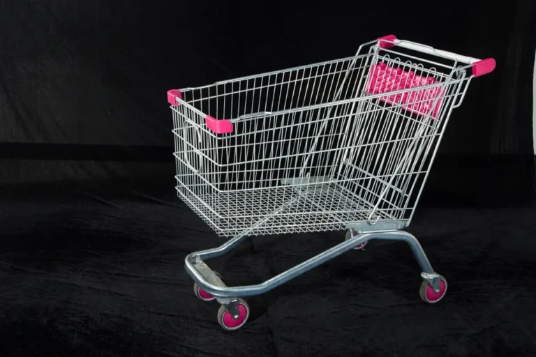 B&H ouvre plus de 160 offres Apple dès 25,99 dollars, panier sous surveillance A metal shopping cart with pink handles and wheels on a dark backdrop, ideal for retail and commerce themes.