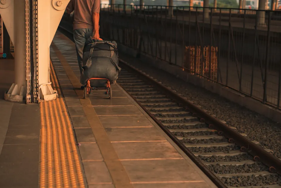 A person with luggage waiting on a platform at an urban train station, highlighting travel and transit.