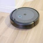 iRobot sous 25 millions de dollars : le Roomba peut-il survivre hors ligne? A sleek, modern robotic vacuum cleaner efficiently operating on a hardwood floor.