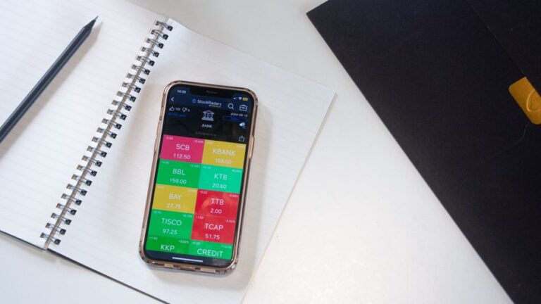 iPhone 16e « raté »? L’iPhone 17e attendu au printemps 2026 A smartphone displays a financial stock market app on a desk with a notebook and pencil.