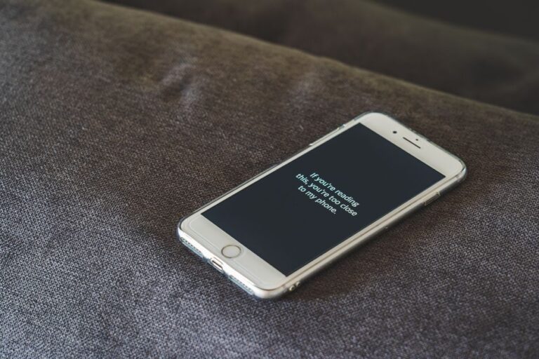 A smartphone with a humorous lock screen message placed on a grey couch, emphasizing privacy.