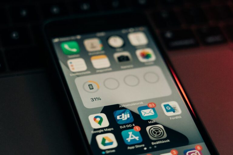 iOS 26.2 bêta 2 du 12 novembre : Liquid Glass rebondit A smartphone with various apps on its screen placed on a keyboard, showing a 31% battery level.