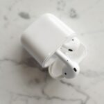 AirPods 4 à 69 dollars le 26 novembre 2025 : le choix de l'ANC A top-view photo of wireless earbuds in a case, placed on a marble surface, showcasing modern technology.