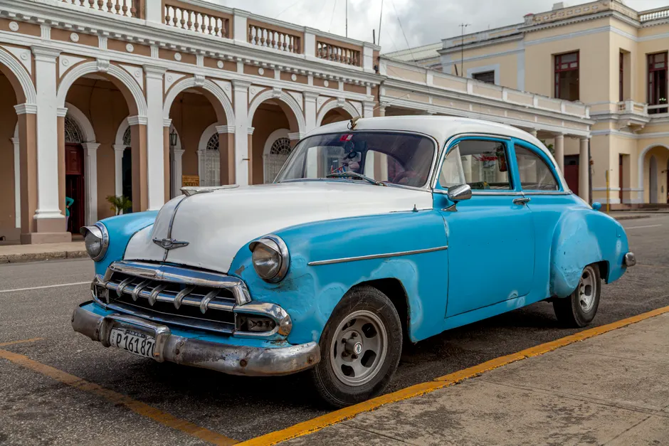 A vintage 1950s American car parked on the streets of Santa Clara, Cuba, showcasing historic architecture.