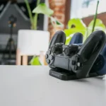 A wireless game controller resting on a charging dock in a modern indoor setting, showcasing gaming technology.