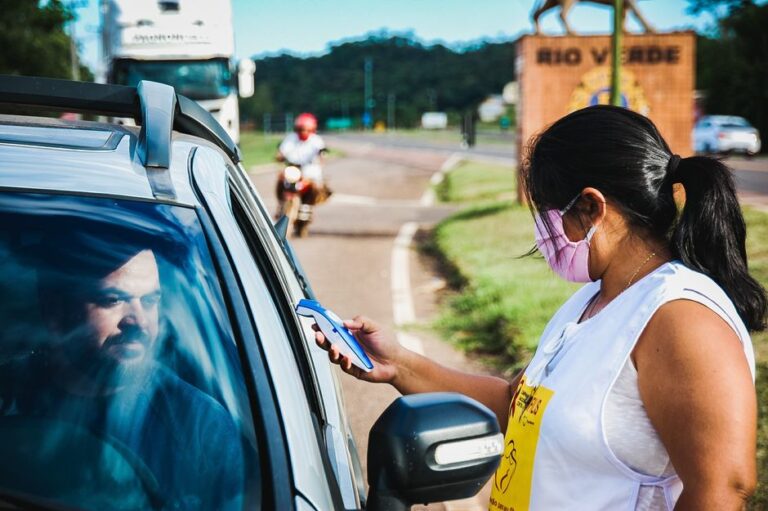 Digital ID sur iPhone le 12 novembre 2025 : le passeport reste aux frontières A woman checks a driver's temperature at a roadside checkpoint during COVID-19 pandemic.