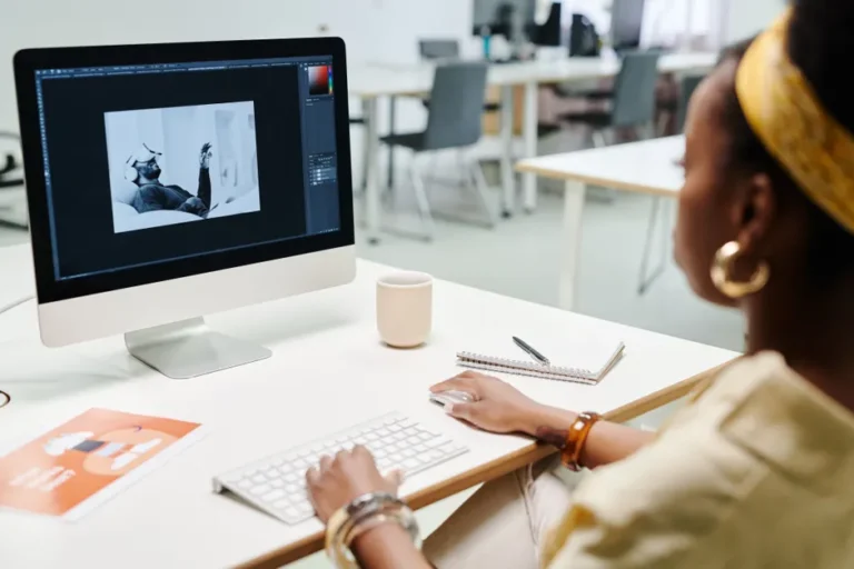Adobe Creative Cloud Pro à 34,97 $ pendant un an : l’offre finit le 28 novembre 2025 A woman using a computer for image editing in a bright, modern office setting.