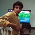MLS Apple TV : l'accord s'arrête en 2029, le Season Pass sort du terrain A young man sitting in a room, focused on a soccer match broadcast on TV.