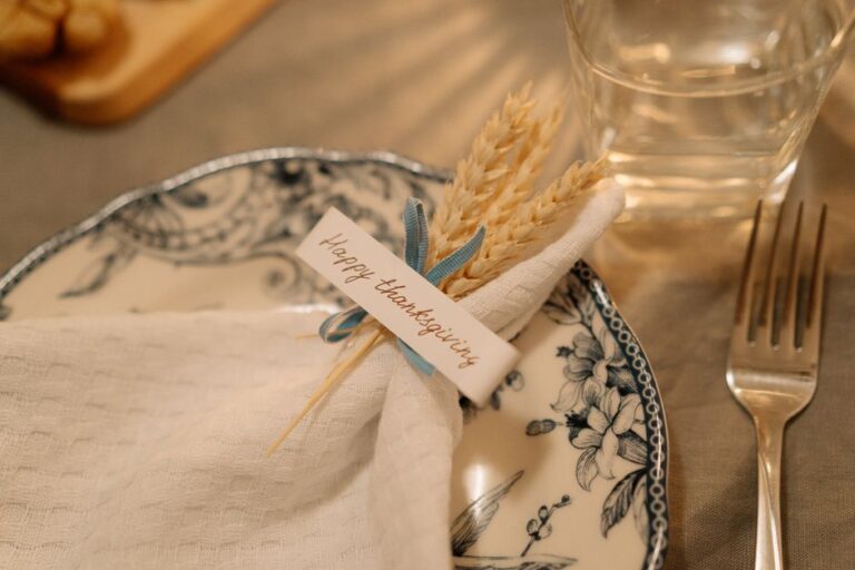 Beautiful Thanksgiving table setting with decorated plate and napkin featuring wheat and a festive greeting card.