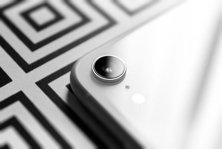Black and white close-up capturing the elegance of a smartphone camera lens against a geometric background.