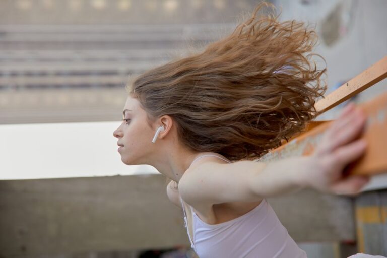AirPods 4 avec ANC à 99,99 $ le 21 novembre 2025 : le Black Friday baisse le volume Captivating side view of a young woman wearing wireless earbuds, caught in motion.