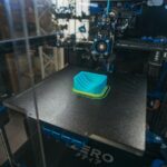Apple imprime du titane en 3D pour ses montres et l’iPhone Air: 900 passages par boîtier Close-up of a 3D printer creating a plastic object in an industrial setting.