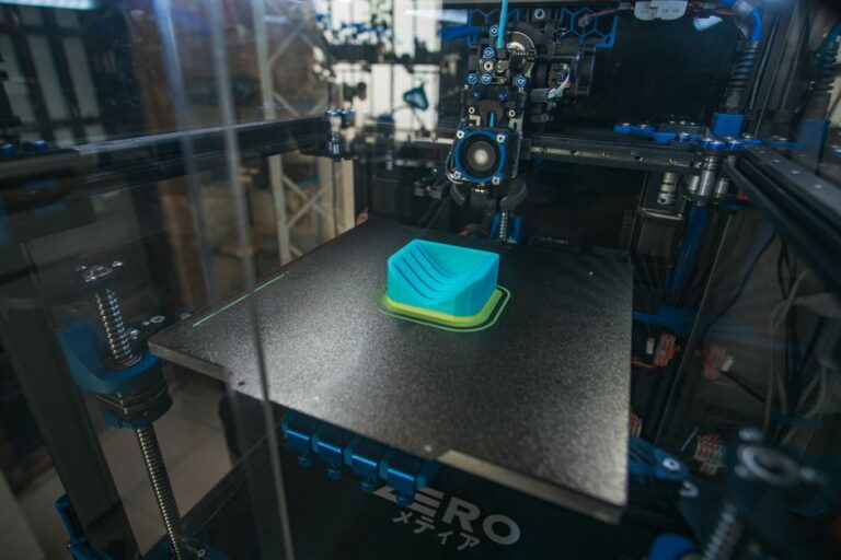 Close-up of a 3D printer creating a plastic object in an industrial setting.