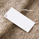 AirPods Black Friday 2025 : Pro 3 à 219,99 $, 4 ANC à 109,99 $ Close-up of a blank white price tag on textured beige fabric, ideal for branding use.