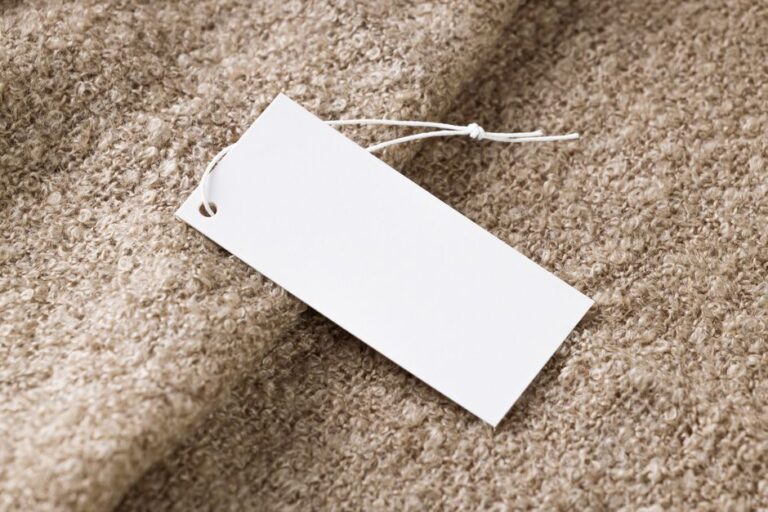 AirPods Black Friday 2025 : Pro 3 à 219,99 $, 4 ANC à 109,99 $ Close-up of a blank white price tag on textured beige fabric, ideal for branding use.
