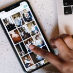 Spatial Scenes sur iPhone 12: iOS 26 donne du relief aux photos, sans Vision Pro Close-up of a person browsing social media on a smartphone next to a laptop.