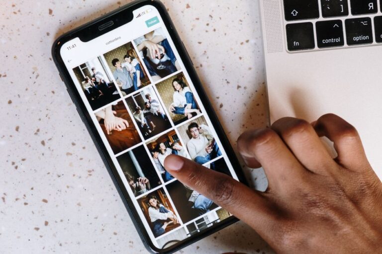 Spatial Scenes sur iPhone 12: iOS 26 donne du relief aux photos, sans Vision Pro Close-up of a person browsing social media on a smartphone next to a laptop.
