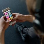 Apple Fitness+ à 9,99 dollars : le projet Health+ en 2026 Close-up of a person listening to music on a smartphone while at the gym, focusing on a streaming playlist app.