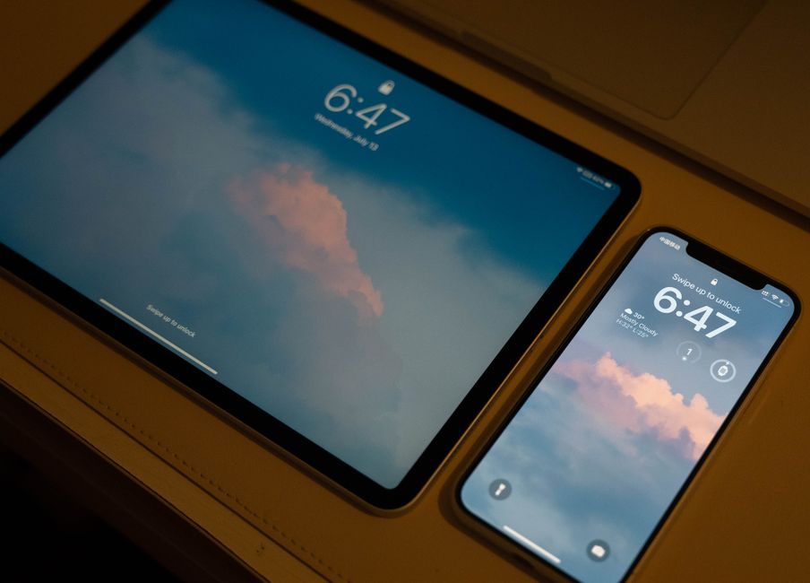 Close-up of a tablet and smartphone with matching lock screen displays at 6:47.