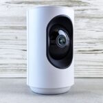 Matter 1.5 officialisé le 20 novembre 2025 : les caméras entrent dans la danse Close-up of a white indoor security camera against a wooden backdrop, showcasing modern design.