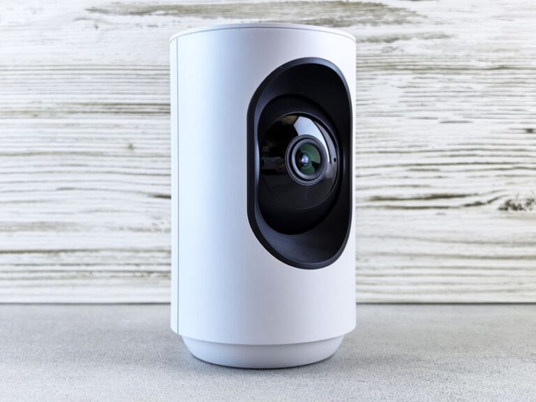 Matter 1.5 officialisé le 20 novembre 2025 : les caméras entrent dans la danse Close-up of a white indoor security camera against a wooden backdrop, showcasing modern design.