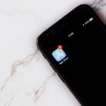Apple relance son recours contre les 2 milliards de dollars de l'App Store Close-up of an iPhone showing a notification on the App Store icon against a marble background.