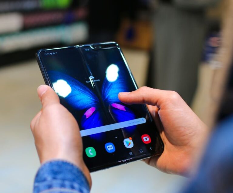 iPhone Fold : écran de 7,8 pouces, sortie visée en 2026 ou 2027 Close-up of hands holding a foldable smartphone showing a butterfly on the screen.