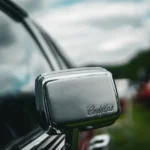 Apple Car Key chez Cadillac : les GM 2026 en approche Detailed close-up shot of a vintage car's side mirror with 'Cadillac' logo, showcasing classic automotive design.