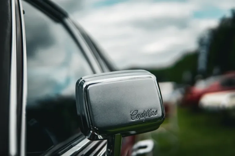 Detailed close-up shot of a vintage car's side mirror with 'Cadillac' logo, showcasing classic automotive design.