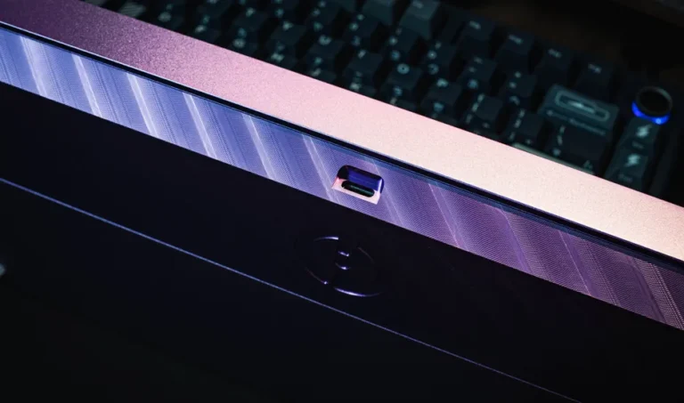 Detailed view of USB-C port on a sleek, purple-edged computer monitor, illuminating during night use.