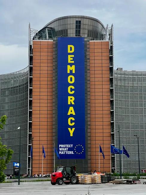 European Commission building with a large democracy banner in Brussels.