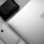 Apple Wallet prépare 4 États pour le permis, cap sur 2027 Flat lay of a sleek workspace featuring a smartphone, laptop, and wallet on a textured background.