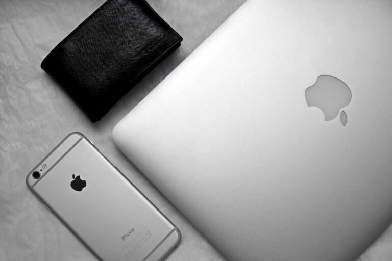 Apple Wallet prépare 4 États pour le permis, cap sur 2027 Flat lay of a sleek workspace featuring a smartphone, laptop, and wallet on a textured background.