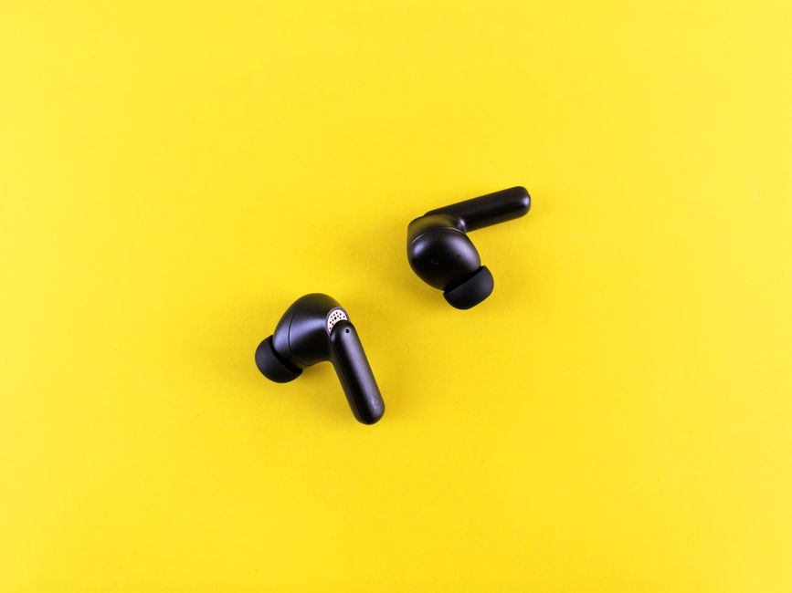 Minimalist black wireless earbuds on a bright yellow backdrop for tech and lifestyle themes.