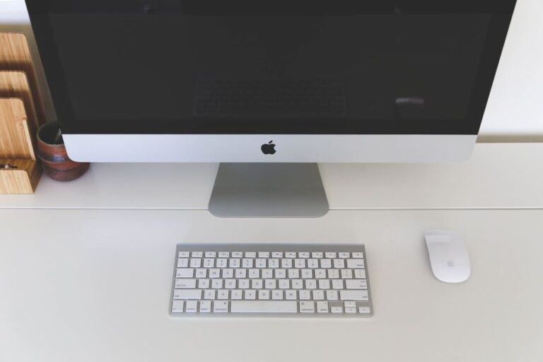 Minimalist home office workspace featuring a desktop computer, keyboard, and mouse on a white desk.