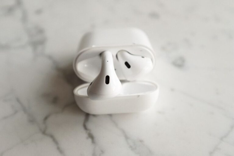 Minimalistic image of wireless earbuds with case open on a sleek marble background.