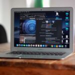 Open MacBook Air with apps and web browser on screen, placed on a wooden table indoors.
