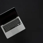 MacBook A18 Pro : 699 à 900 dollars, le pari qui coince Overhead view of a MacBook laptop on a dark desk, showcasing modern technology and minimalism.