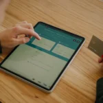 iPad 11 à environ 279 dollars au Black Friday 2025 : le stockage grimace Person making an online payment using a tablet and credit card on a wooden desk.