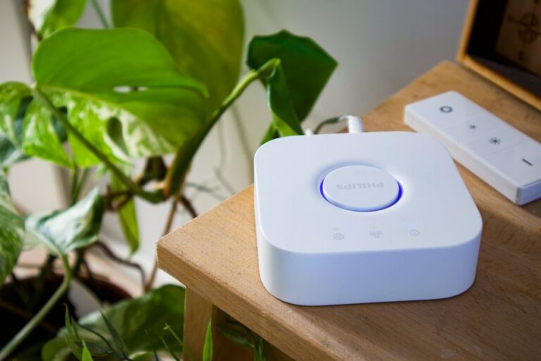 Philips Hue dépasse 100 produits en 2025 : le jardin clos change d’ampoule Philips smart hub beside a leafy plant in a stylish indoor setting, showcasing modern home automation.