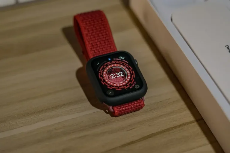 Apple Watch SE 2 à 159,99 dollars : le chrono tourne Red-banded smartwatch displayed on a wooden surface, highlighting digital watch face.
