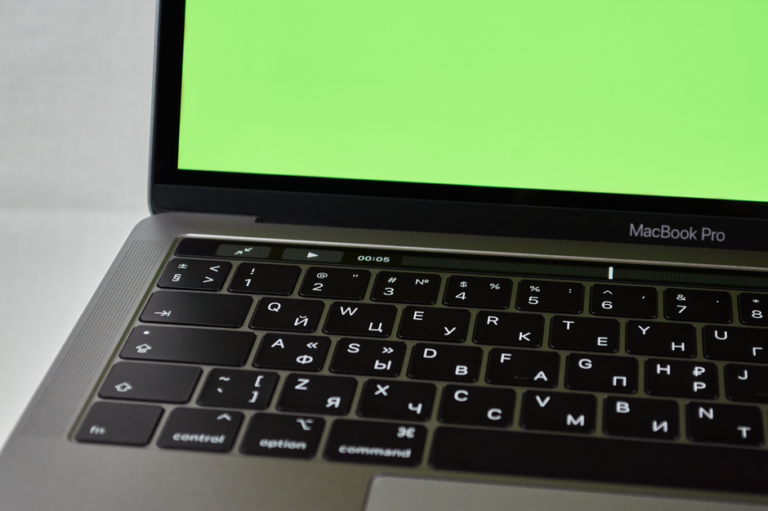 MacBook Pro M4 à 1 299 $ le 18 novembre 2025 : le M5 rôde Russian keyboard MacBook Pro with a green screen. Modern electronic device.