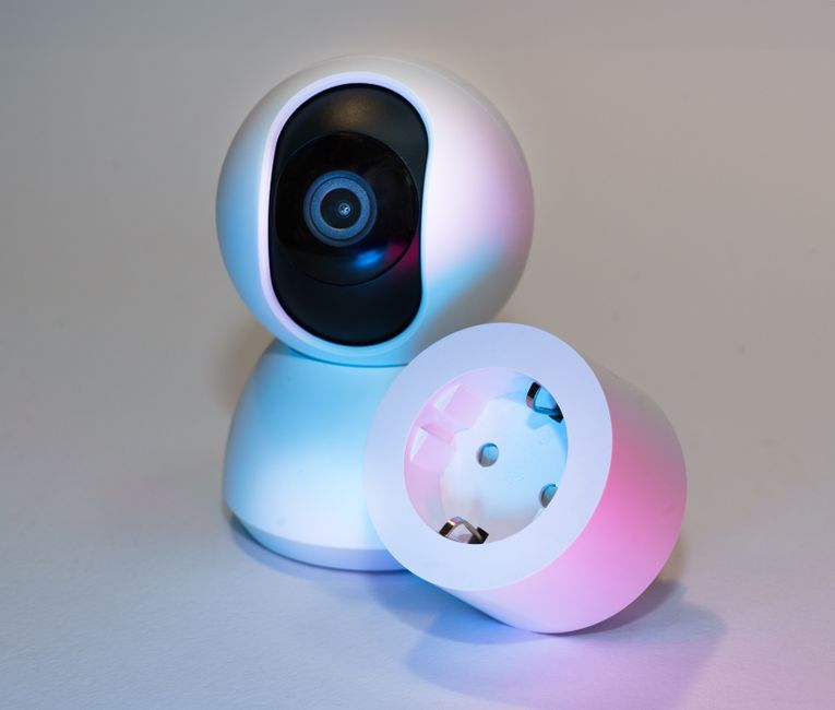 Matter 1.5 ajoute les caméras en novembre 2025, Apple Home attend Smart home security camera and plug socket on a neutral background.