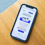 iPhone 17 : Apple atteint 25 % du marché chinois en octobre 2025, le Mate 80 arrive Smartphone displaying e-commerce advertisement on wooden surface, ideal for digital marketing themes.