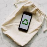 iPhone Pocket dès 149,95 dollars : l’iPod Sock revient, la praticité tousse Smartphone displaying recycling icon on a drawstring pouch. Eco-conscious and sustainable theme.