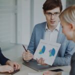 Apple réorganise sa force commerciale le 24 novembre 2025 : des dizaines de postes touchés Team of professionals discussing sales strategies with charts in a modern office.