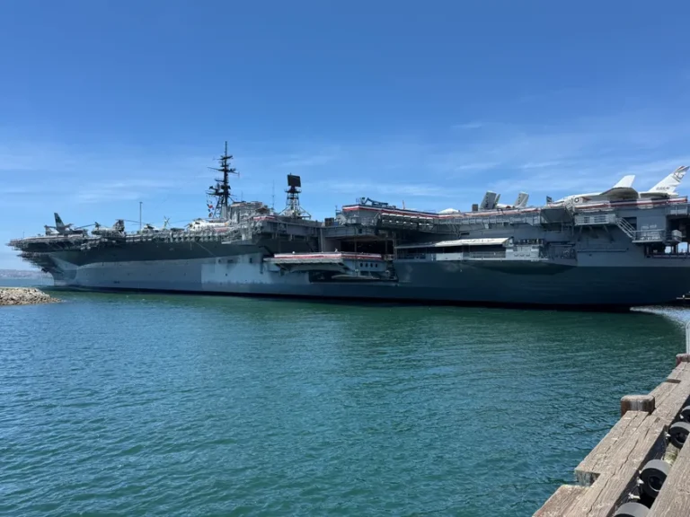 Apple Vision Pro : Flight Ready, 14 minutes sur le Nimitz, casque requis The USS Midway, a historic aircraft carrier, docked in the scenic San Diego Harbor, under clear blue skies.