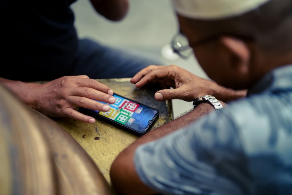 Two individuals play a mobile game on a smartphone outdoors in Jakarta, Indonesia.